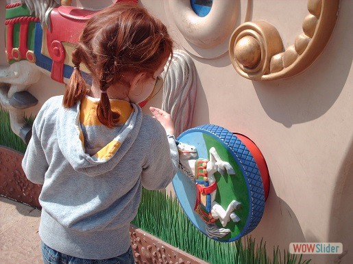 a little girl is standing in font of the tactile wall
